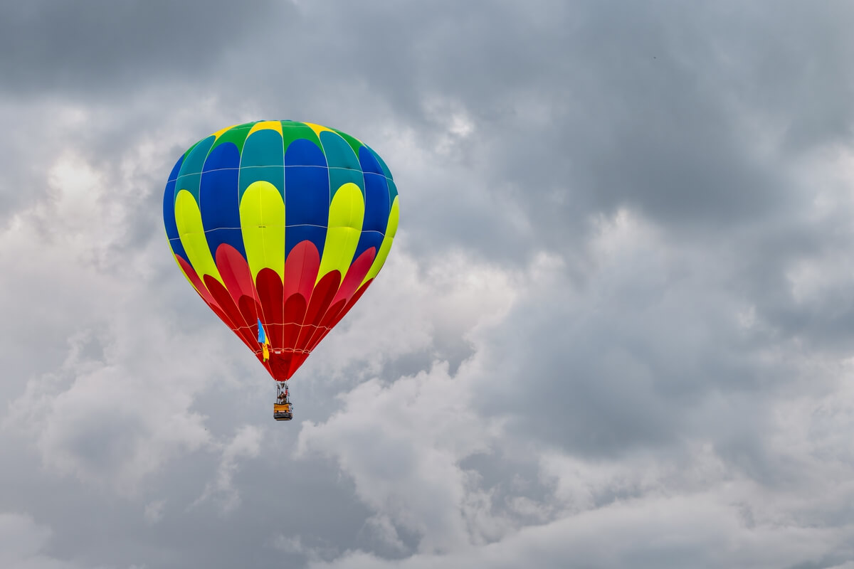 Vivid Balloon Against Dark Sky: A Colorful Hot Air Balloon Amidst the Clouds