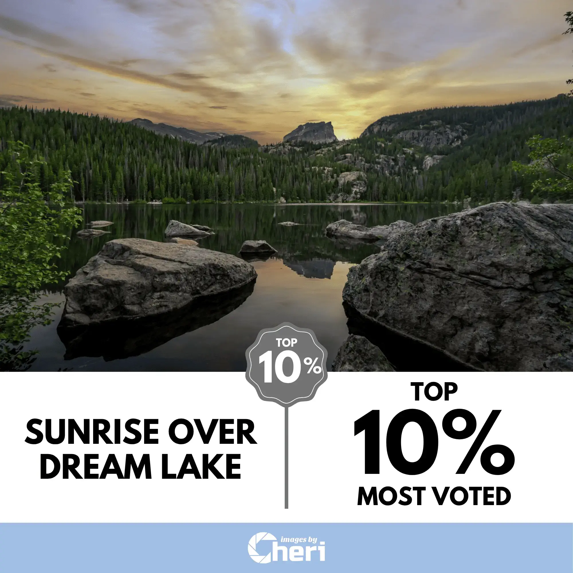 Wide landscape photograph of a colorful sunrise over Dream Lake in Rocky Mountain National Park, featuring two large boulders in the foreground and a mountain peak in the distance. The image was voted Top 10%.